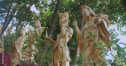 Dolly shot of female buddha statues in a row. Ten Thousand Buddhas Monastery, Sha Tin, Hong Kong. Peaceful golden religious sculptures in the sunlight. High dynamic range footage. photo