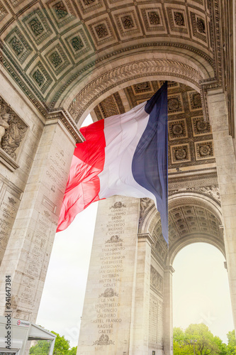 View of Arc de Triomp with flag of France waving in wind on Place de Gaulle in Paris, France © lara-sh