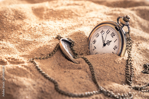 an old pocket watch with a chain lying in the sand