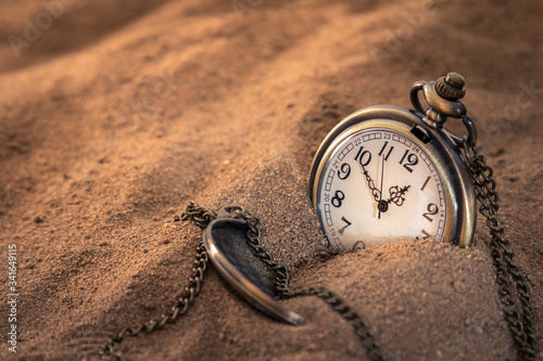 an old pocket watch with a chain lying in the sand