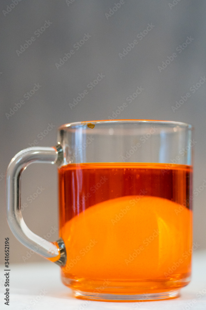 Chicken egg in food coloring in a mug. Coloring of Easter eggs Chicken egg in food coloring in a mug. Coloring of Easter eggs