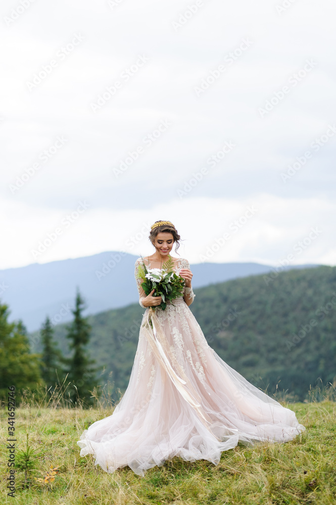 Portrait of a beautiful bride in the mountains. The girl holds a wedding bouquet in her hands.