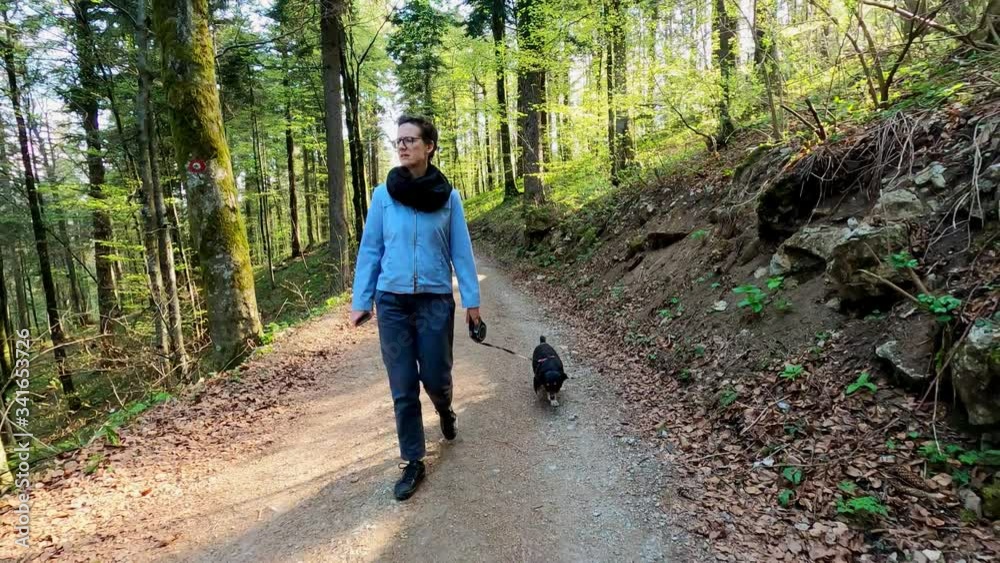 Young woman walking with small black dog in the woods footage with action camera
Young woman walking with small black dog in the woods footage with action camera