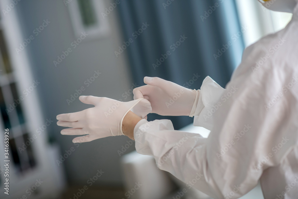 Person in white workwear wearing protective gloves