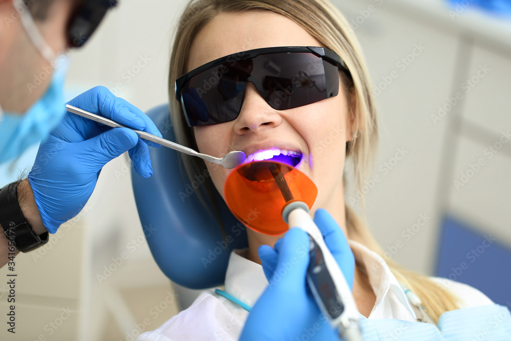 Stomatologist examines mouth of his patient with UV. Selective focus