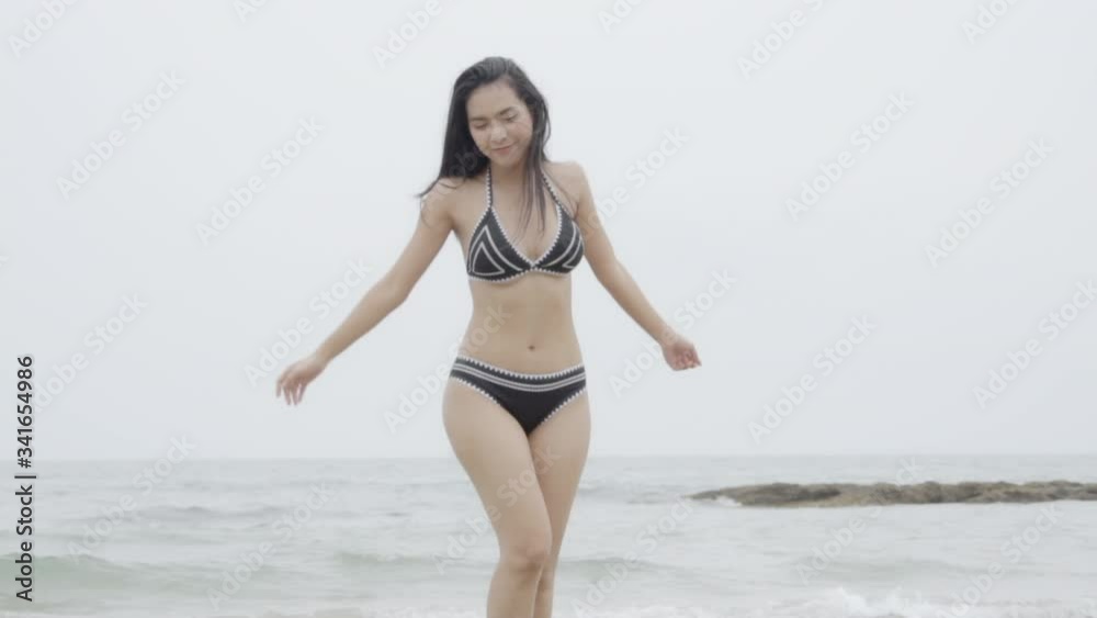 Beautiful tanned young asian woman in bikini walking at the beach, girl sexy happy and smiling on summer travel in vacation, woman relax wearing swimwear or swimsuit fashion running in tropical. Beautiful tanned young asian woman in bikini walking at the beach, girl sexy happy and smiling on summer travel in vacation, woman relax wearing swimwear or swimsuit fashion running in tropical.