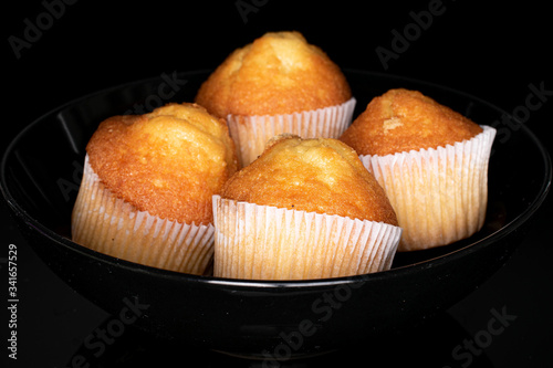 Group of four whole small baked muffin isolated on black glass