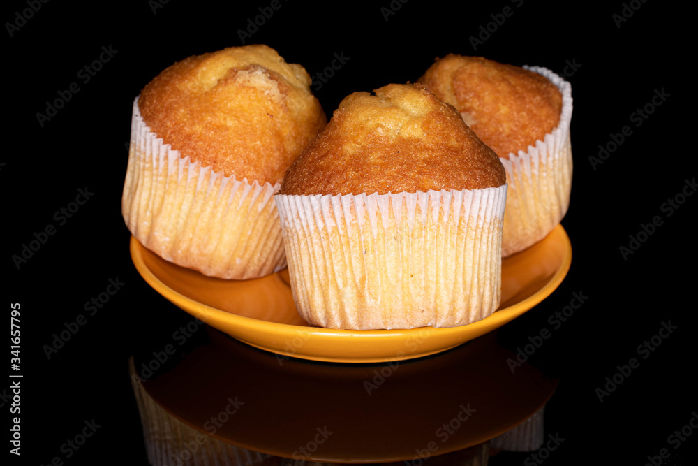 Group of three whole small baked muffin on plate isolated on black glass Group of three whole small baked muffin on plate isolated on black glass