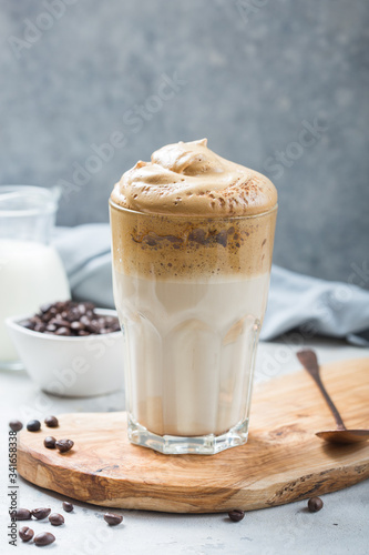 Dalgona frothy coffee in glass on grey. Trend korean drink latte with foam of instant coffee. Close up. © Maria