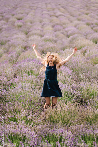 Fototapeta Naklejka Na Ścianę i Meble -  Beautiful girl in dress jumping and flying long hair on purple lavender field. Beautiful woman walk on the lavender field on sunset. Enjoy the floral glade, summer nature. Hairstyle.