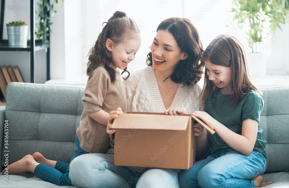 Mother and daughters are unpacking cardboard Mother and daughters are unpacking cardboard