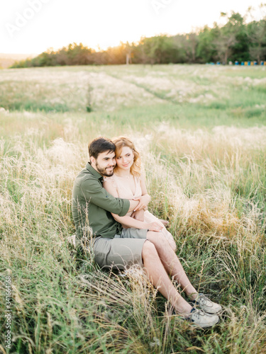 Young couple in love outdoor. Stunning sensual outdoor portrait of young stylish fashion couple posing in summer in field. Film photography. Pretty family hugging and flirting in an park
