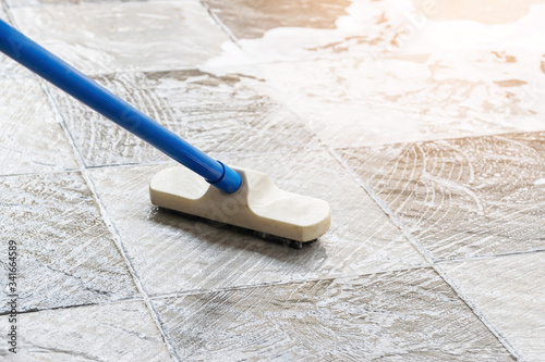 Cleaning the tile floor with floor scrubber brush and water.