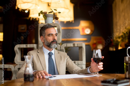 Handsome mature man drinking glass of red wine in restaurant