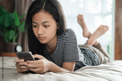 Slika na platnu teenager using mobile smart phone at home while laying on the bed