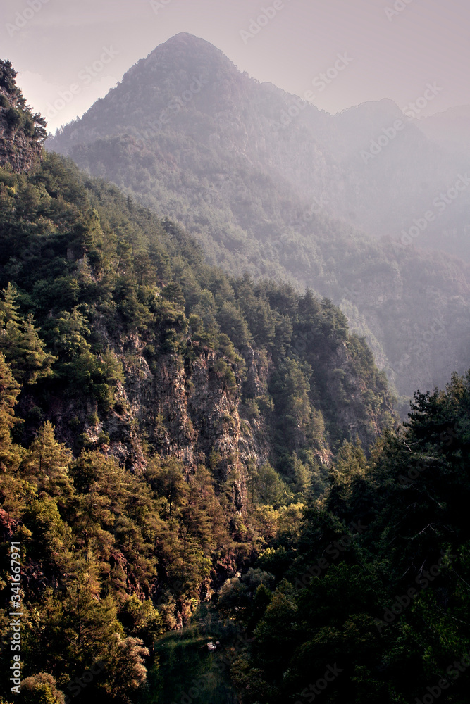Obraz premium mountain view scenery with a bit of haze due to sunrise time after, 20 min morning hike inside the mountain pausing in scenery that combines the river and the crispy mountains surrounding it praise