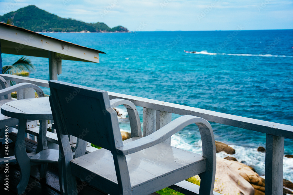 Fototapeta premium Chair with table set on balcony hotel room with ocean view background. Nice sea view from a balcony of a hotel. 