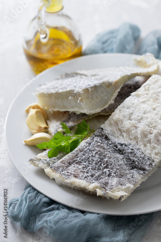 dry cod fish on white plate on ceramic background