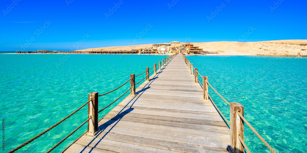 Wooden Pier at Orange Bay Beach with crystal clear azure water and white beach - paradise coastline of Giftun island, Mahmya, Hurghada, Red Sea, Egypt.