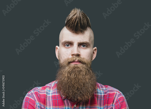 Young man close up portrait. Punk styled men with Mohawk hairstyle is smiling. Isolated on gray background photo