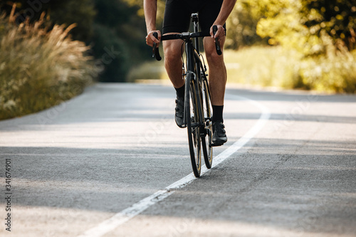 Fototapeta Naklejka Na Ścianę i Meble -  Close up of mature man with strong body shape in cycling outfit doing sport activity on bike. Concept of healthy lifestyle and regular training.