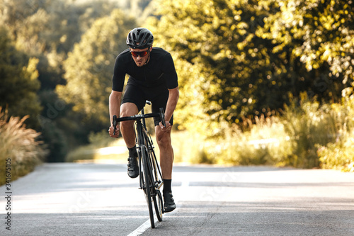Full length portrait of active man in sport clothing and protective helmet riding bike with blur background of summer nature. Concept of workout and races. © Tymoshchuk
