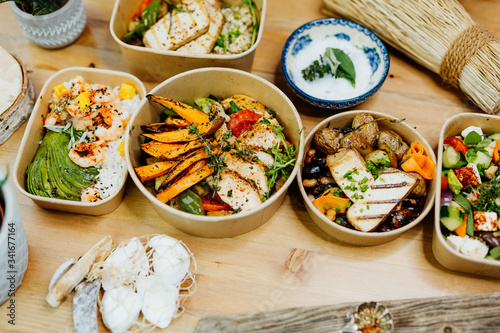 Various healthy and vitamin-rich dishes and food in an ecobox delivered by a delivery service, ordered online, decorated with bundles of straw, mussels and cacti, in a Mediterranean style photo