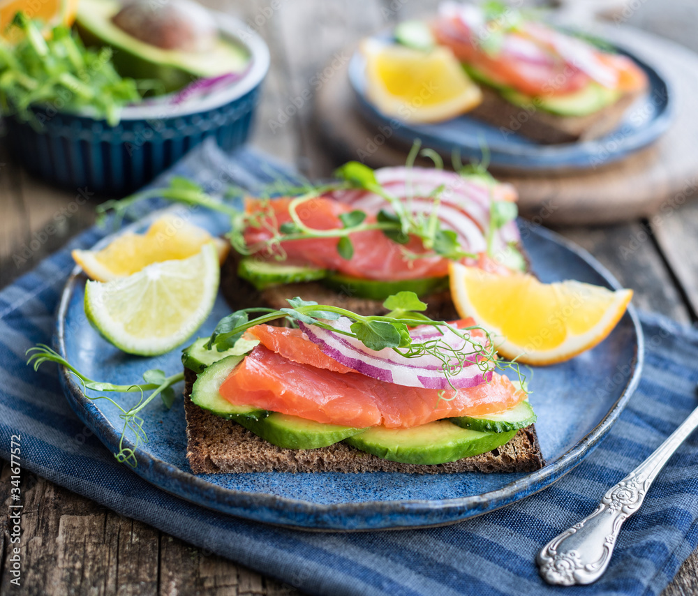 Sandwiches with red fish and vegetables on a blue plate.
