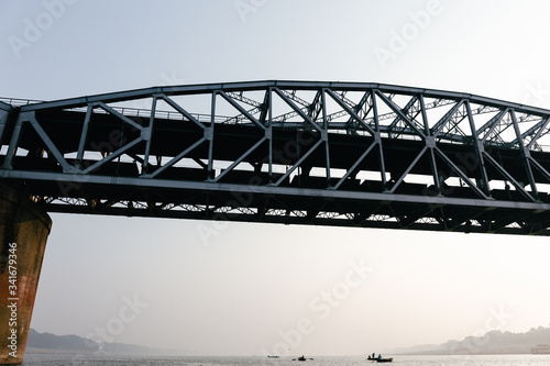 Close up shot of a portion of the indian railway bridge of Varanasi on the holy river Ganges. View from below during a boat ride on the river at dawn.