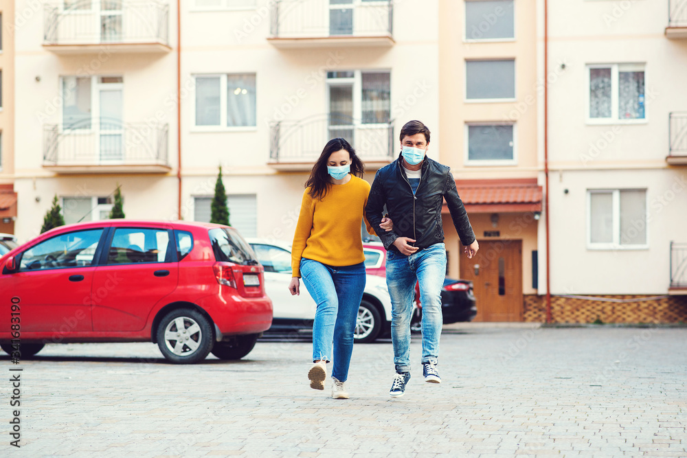 Coronavirus epidemic. Young couple wearing face masks at street.