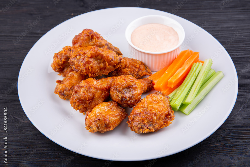Fried legs and wings with breading, served with sauce and vegetables Fried legs and wings with breading, served with sauce and vegetables