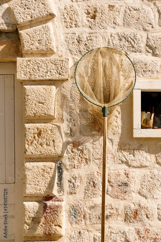Fishing landing net against the background of a stone wall photo