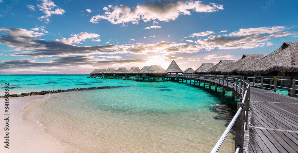 Scenic panoramic landscape view of  luxury overwater bungalows at the beach and lagoon during sunset in Moorea, French Polynesia.