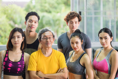 A group of fitness players of a variety of age groups, including the elderly, middle-aged and young people, both women and men They wear exercise clothes, standing in the gym. © MPIX.TURE