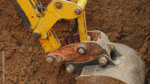 Earthmoving equipment at a construction site. Excavator bucket removes ground from trench