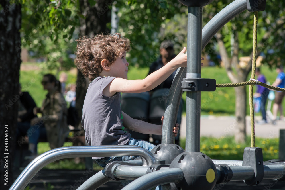 Six-year-old boy plays on the playground in the city park. Six-year-old boy plays on the playground in the city park.