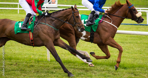 Close up on two race horses and jockeys competing for position on the track