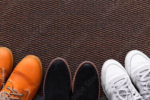 Different men's and women's shoes, pair of sneakers on a shoe mat, top view.