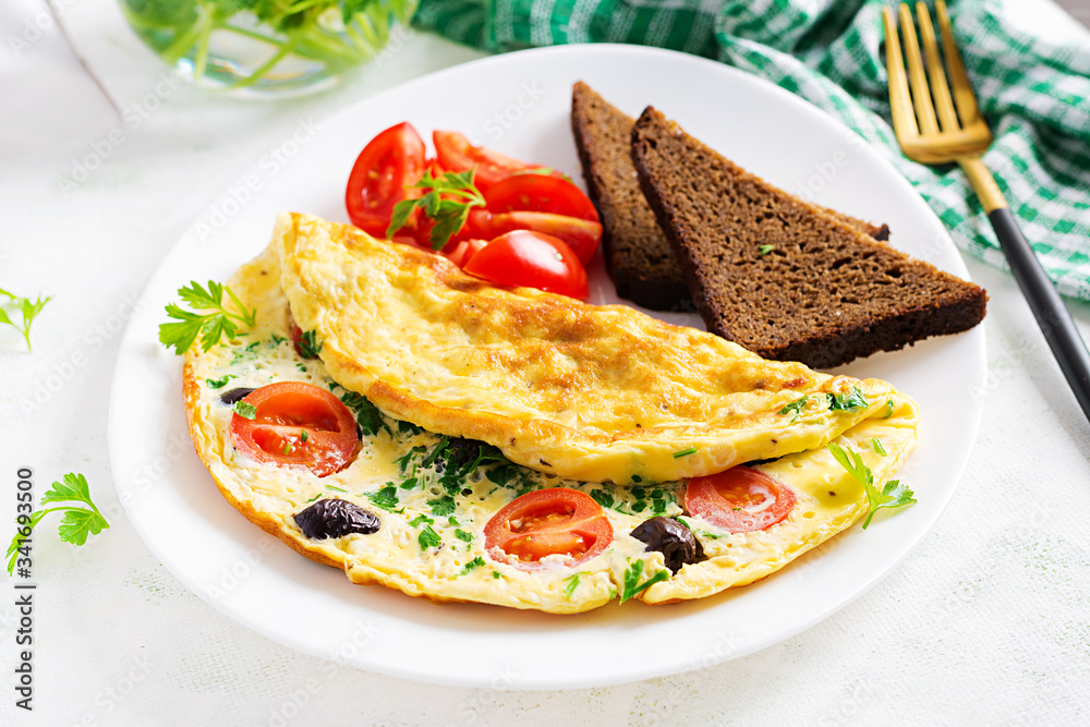 Breakfast. Omelette with tomatoes, black olives, cottage cheese and green herbs on white plate.  Frittata - italian omelet.