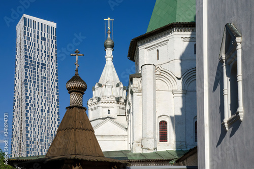 City of contrasts. Trinity (Troitskaya) church against modern skyscraper. Troitskoye-Golenishchevo, Moscow, Russia. photo