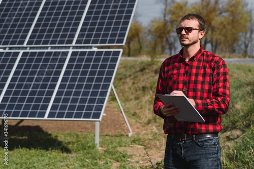 solar panels and blue sky.Man standing near solar panels. Solar panel produces green, environmentally friendly energy from the sun. © Serhii