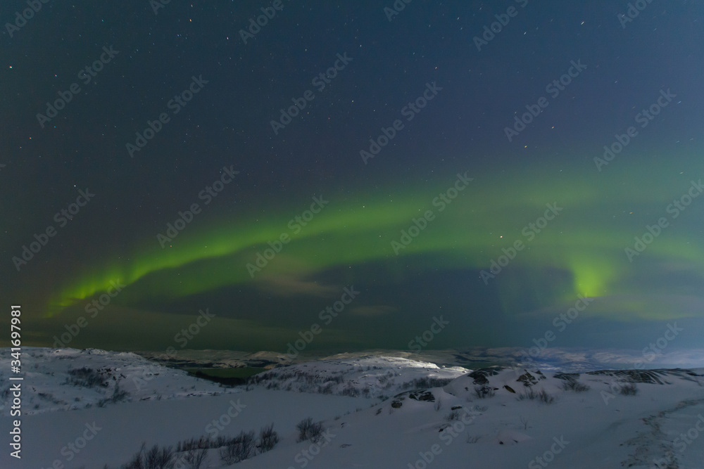 Aurora and stars in the sky .The rocks and ground are covered with snow.Arctic.