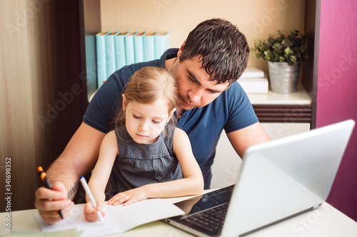 The father helps the daughter to do lessons on distance learning. Online education using a laptop. 