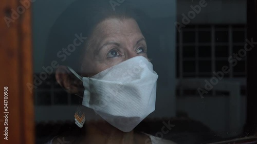 Woman in quarantine for Covid-19 looking out the window with eyes of hope photo