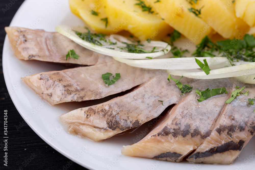Herring in oil, with cooked potatoes, onions and greens