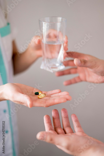 Hands holding glass of water and pills