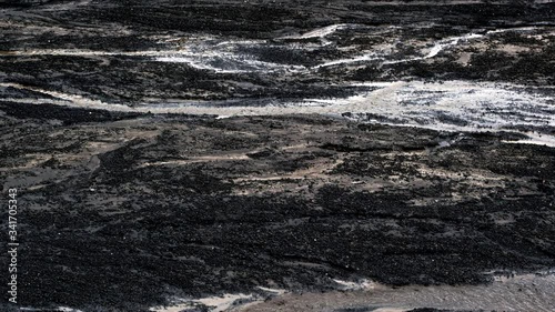 Glacier with ash in the ice with melted water and Icelandic landscape. Little trickle because of melting ice of a glacier in Iceland