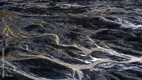 Glacier with ash in the ice with melted water and Icelandic landscape. Little trickle because of melting ice of a glacier in Iceland