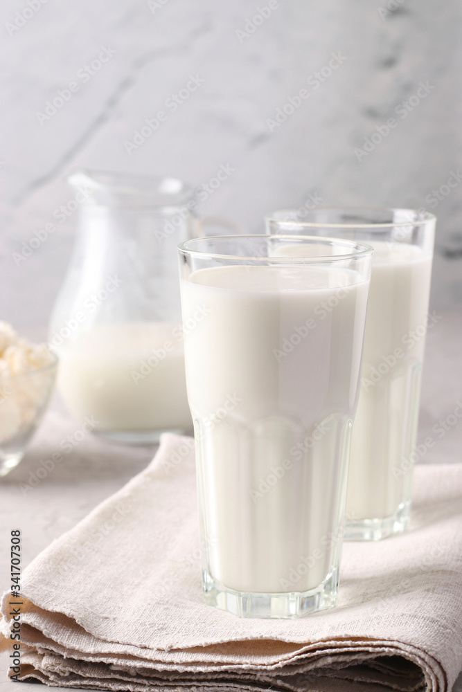 Kefir or Ayran fermented drink in a glasses and jug, as well as cottage cheese in a bowl on light gray background, Vertical format Kefir or Ayran fermented drink in a glasses and jug, as well as cottage cheese in a bowl on light gray background, Vertical format