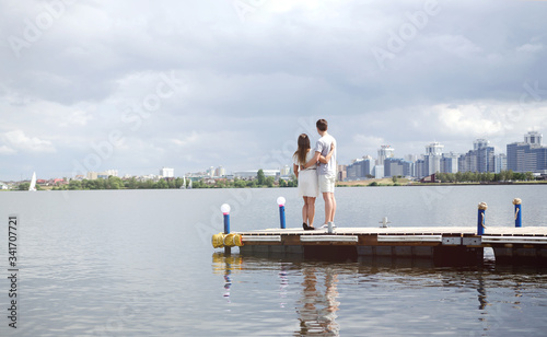 Lovers stand on the pier and look at the lake and the city  lovers relax